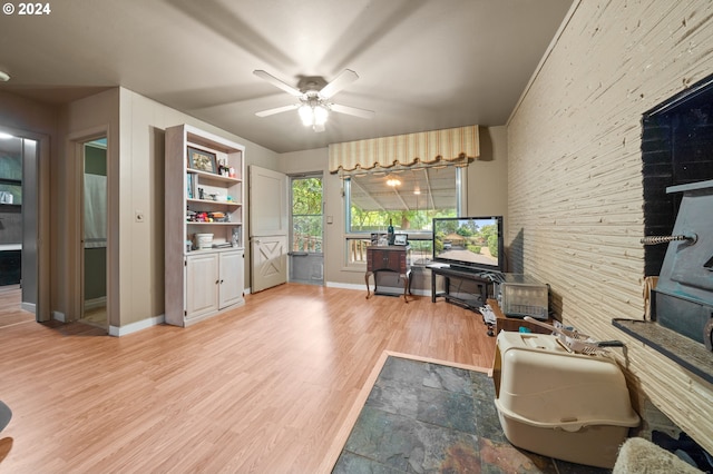 office space with light hardwood / wood-style floors, a wood stove, and ceiling fan