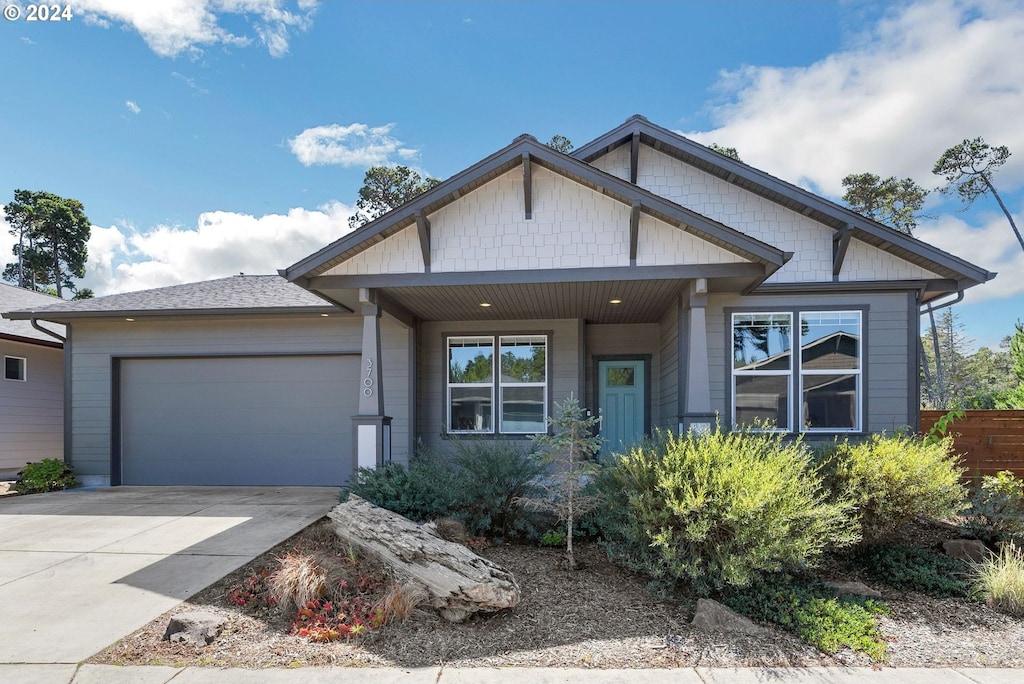 craftsman-style house with concrete driveway, roof with shingles, and an attached garage