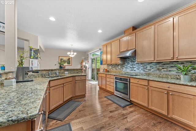 5898 SE Thornapple St, Hillsboro, OR 97123 - kitchen featuring oven, under cabinet range hood, a sink, a chandelier, and black electric cooktop