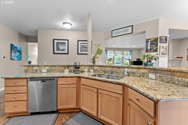 5898 SE Thornapple St, Hillsboro, OR 97123 - kitchen with stainless steel dishwasher, wood finished floors, a sink, light stone counters, and a peninsula