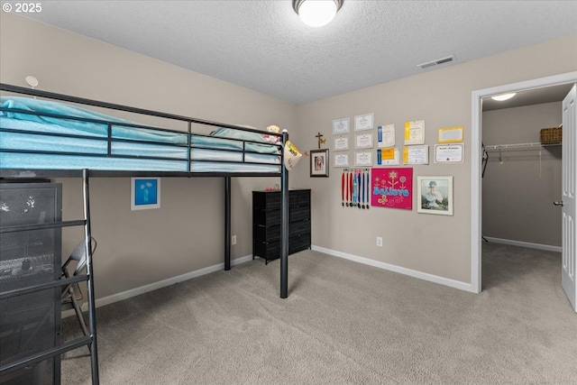 5898 SE Thornapple St, Hillsboro, OR 97123 - unfurnished bedroom with carpet flooring, a textured ceiling, baseboards, and a walk in closet