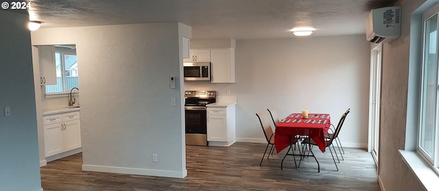 kitchen with white cabinets, an AC wall unit, sink, dark hardwood / wood-style flooring, and stainless steel appliances