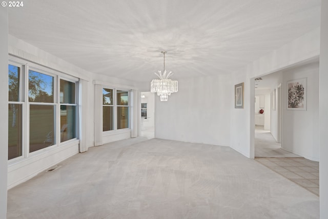 carpeted empty room with a notable chandelier