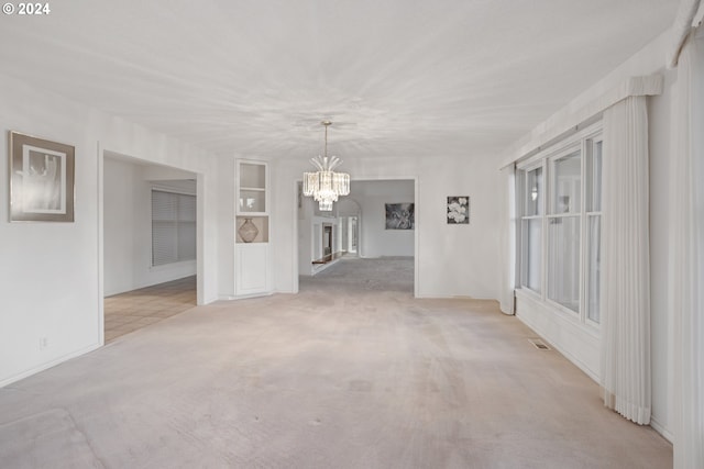 unfurnished dining area with light carpet, a notable chandelier, and built in features