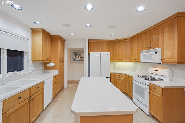 kitchen featuring white appliances, a center island, and sink