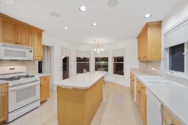 kitchen with white appliances, an inviting chandelier, a center island, decorative light fixtures, and sink