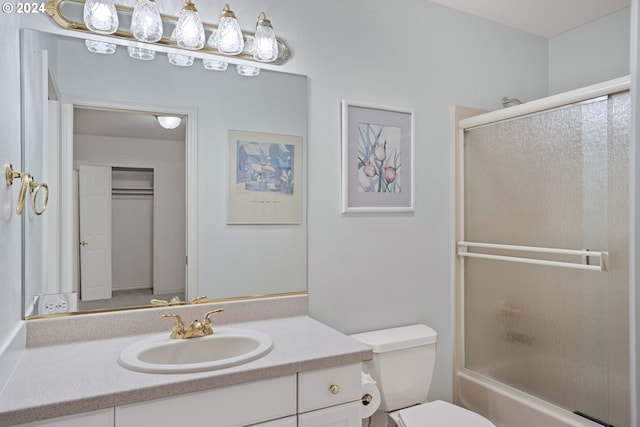 full bathroom featuring combined bath / shower with glass door, vanity, and toilet