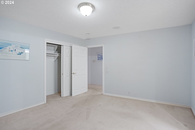 unfurnished bedroom featuring a textured ceiling, light carpet, and a closet