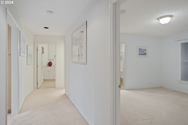 hall with a textured ceiling and light carpet