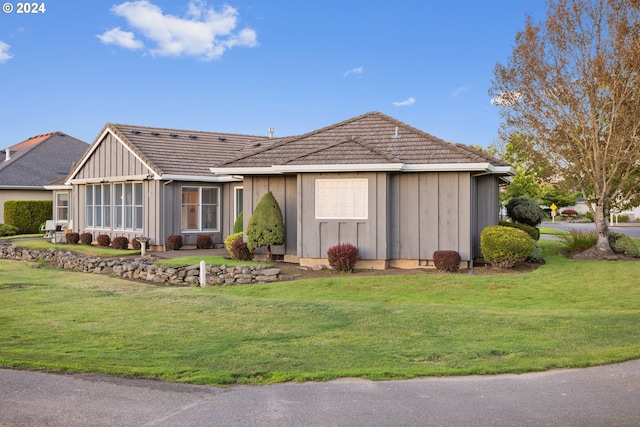 single story home with a front yard and a sunroom