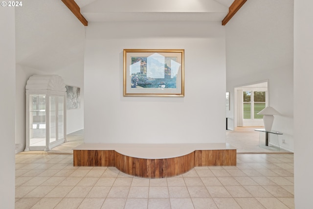 empty room with beam ceiling, light tile patterned floors, and high vaulted ceiling