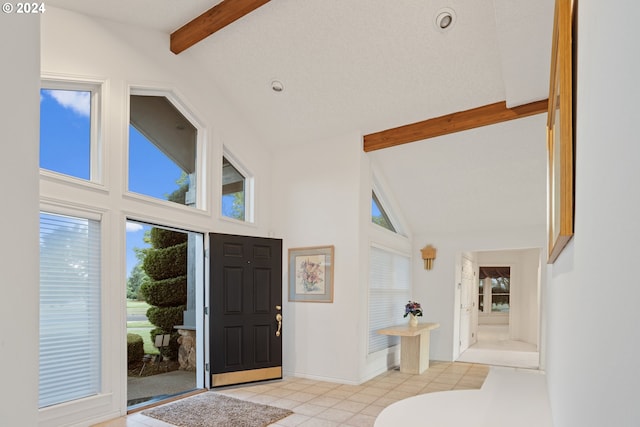 tiled entrance foyer featuring a textured ceiling, beam ceiling, and high vaulted ceiling