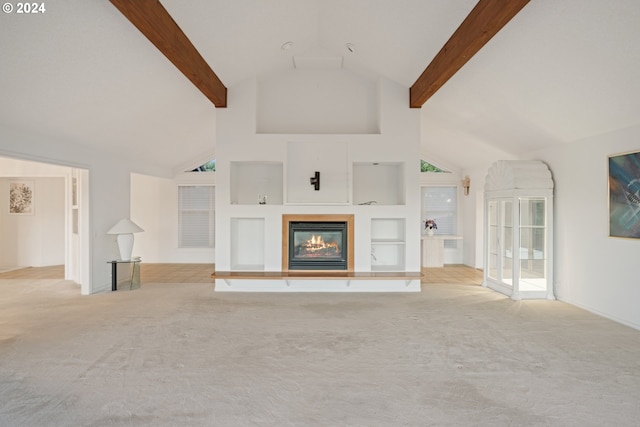 unfurnished living room with built in shelves, light colored carpet, and beamed ceiling