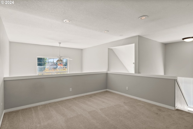 empty room featuring a textured ceiling and light colored carpet