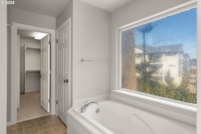 bathroom with a textured ceiling and a relaxing tiled tub