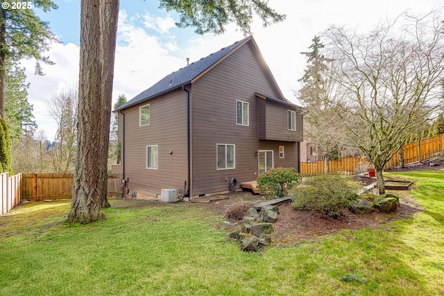 rear view of house featuring central AC and a lawn