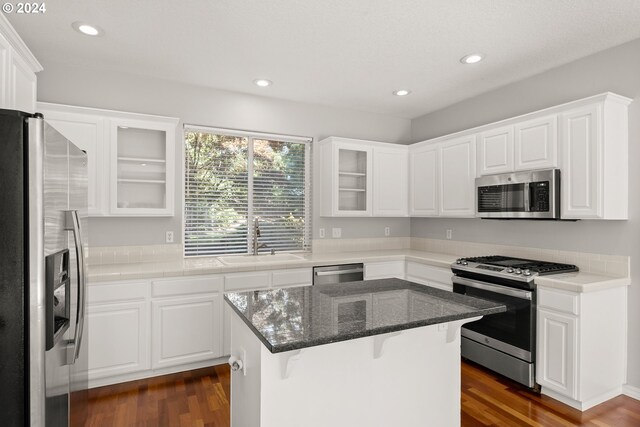 kitchen with white cabinets, a kitchen island, dark hardwood / wood-style floors, sink, and stainless steel appliances