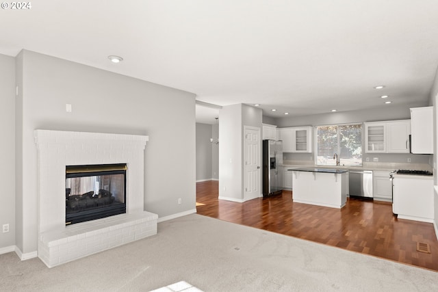 kitchen featuring appliances with stainless steel finishes, a breakfast bar area, white cabinets, a center island, and a fireplace