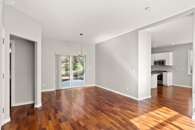 unfurnished living room with dark hardwood / wood-style flooring and an inviting chandelier