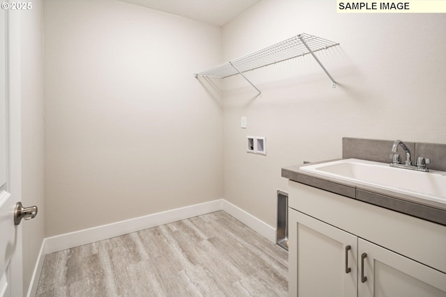 laundry area featuring hookup for a washing machine, sink, cabinets, and light hardwood / wood-style flooring