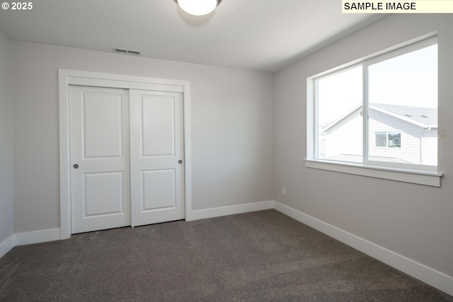 unfurnished bedroom featuring dark colored carpet and a closet