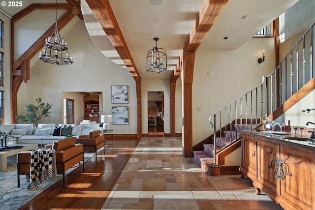 foyer with beam ceiling, a high ceiling, and a chandelier