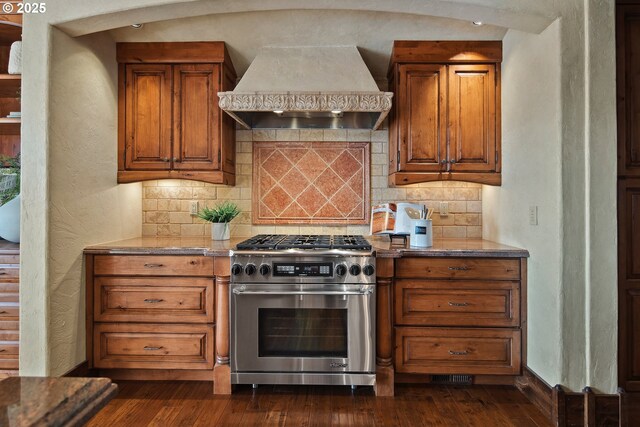 kitchen with backsplash, stainless steel range, custom exhaust hood, and dark wood-type flooring