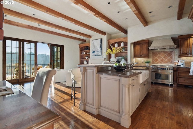 kitchen with premium range hood, a kitchen island, sink, a kitchen breakfast bar, and high end stainless steel range oven