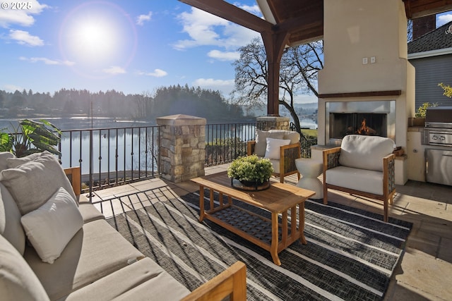 wooden terrace with a water view, area for grilling, and an outdoor living space with a fireplace