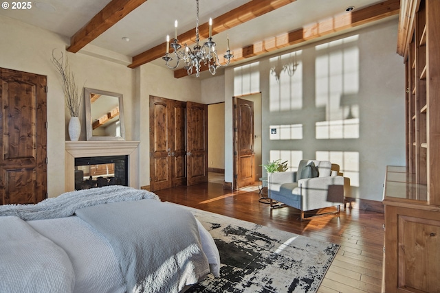 bedroom featuring beamed ceiling, a multi sided fireplace, dark hardwood / wood-style flooring, and an inviting chandelier