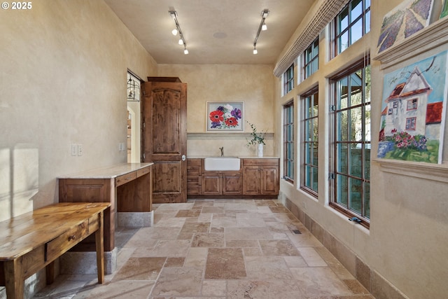 interior space with a high ceiling, rail lighting, and sink