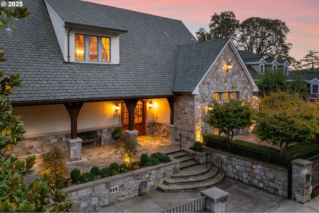 back house at dusk with a patio area