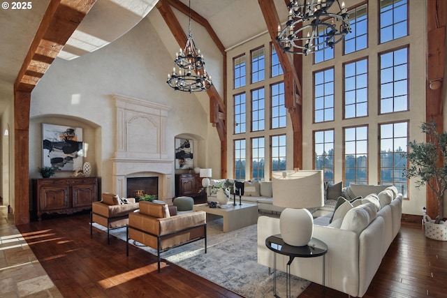 living room featuring dark hardwood / wood-style floors, an inviting chandelier, a towering ceiling, a fireplace, and beam ceiling