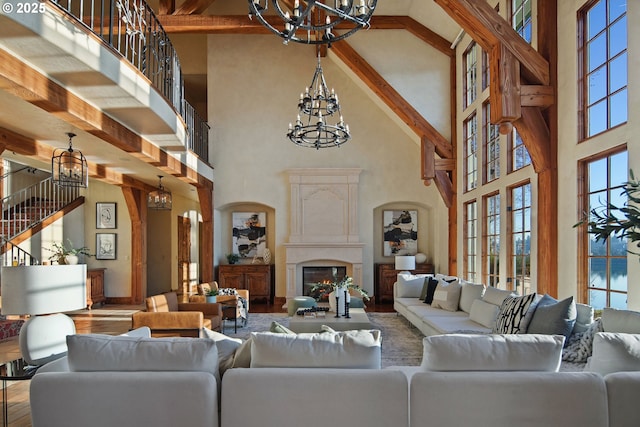 living room with a high ceiling, a high end fireplace, a wealth of natural light, and an inviting chandelier