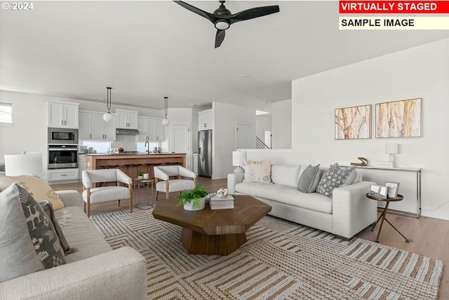 living room with light hardwood / wood-style floors, sink, and ceiling fan