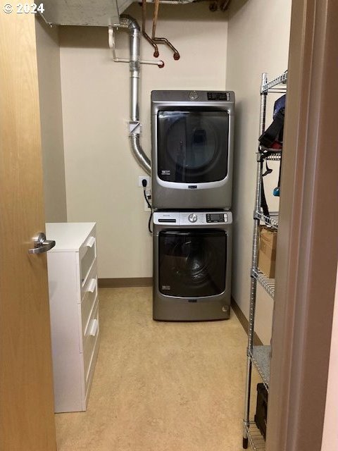 laundry room featuring stacked washer / dryer and light colored carpet