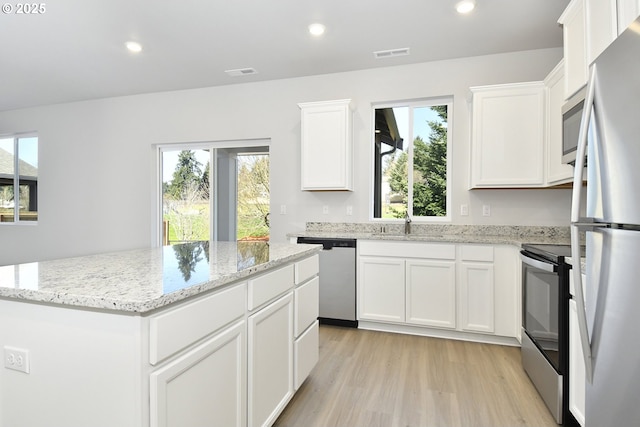 kitchen featuring a kitchen island, white cabinetry, light hardwood / wood-style flooring, and appliances with stainless steel finishes