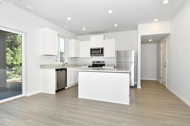 kitchen featuring white cabinetry, appliances with stainless steel finishes, light wood-type flooring, and a kitchen island