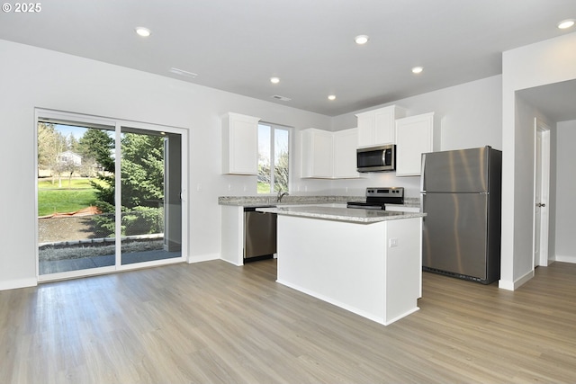 kitchen featuring light hardwood / wood-style flooring, stainless steel appliances, white cabinetry, and a kitchen island