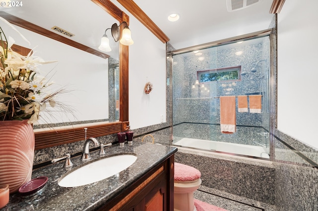 full bathroom with vanity, toilet, crown molding, and bath / shower combo with glass door