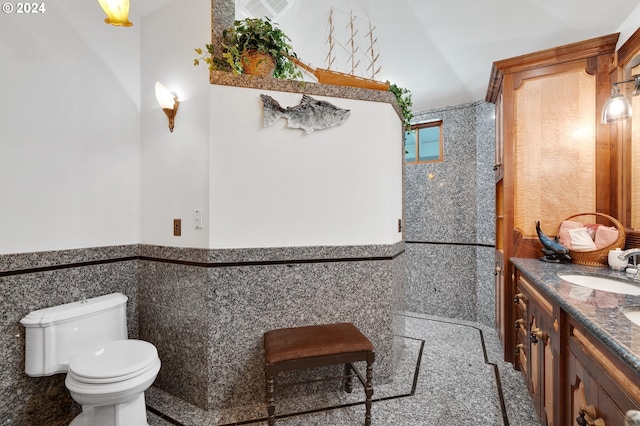 bathroom with vanity, toilet, and tile walls