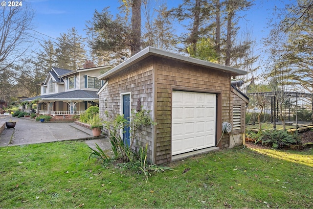 view of home's exterior with an outbuilding, a porch, a garage, and a lawn