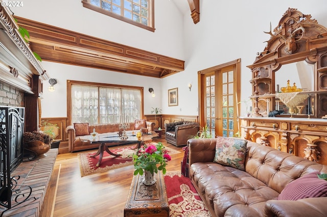 living room with beam ceiling, a wealth of natural light, a towering ceiling, and light wood-type flooring