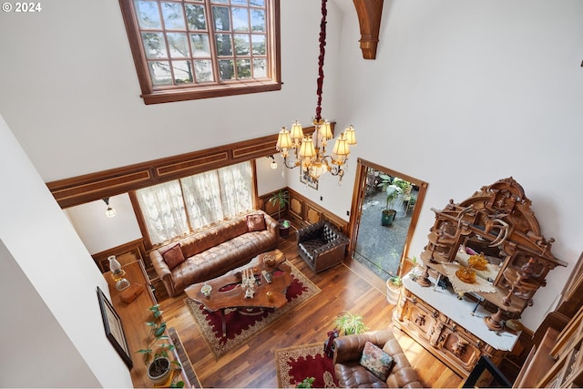 living room featuring plenty of natural light, hardwood / wood-style floors, a high ceiling, and an inviting chandelier