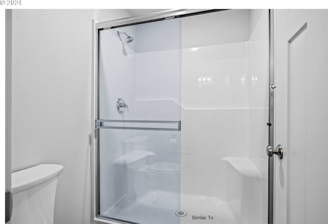 bathroom featuring a stall shower, toilet, and a textured wall