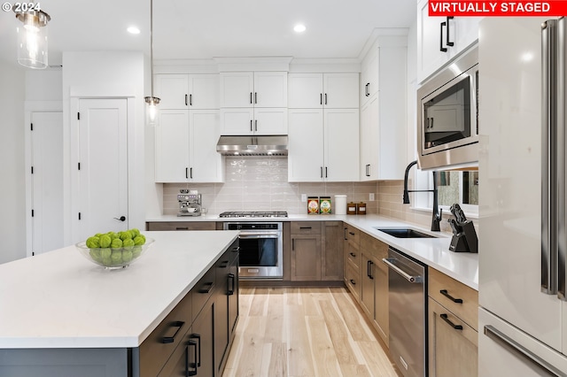 kitchen with pendant lighting, appliances with stainless steel finishes, a kitchen island, white cabinetry, and sink