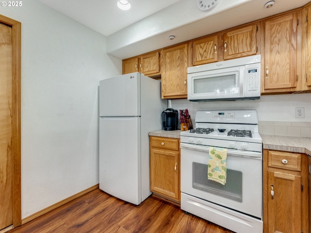 kitchen featuring dark wood finished floors, white appliances, light countertops, and baseboards