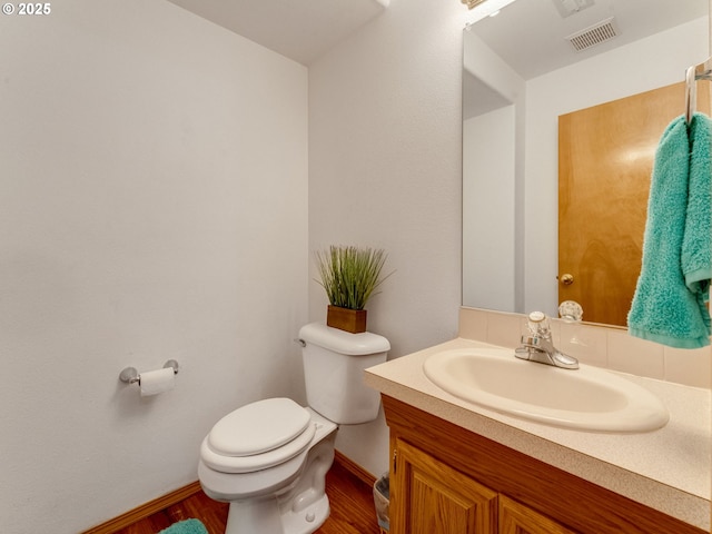 bathroom with vanity, wood finished floors, visible vents, baseboards, and toilet