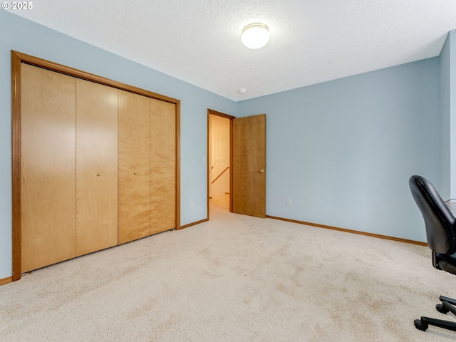 unfurnished office with carpet flooring, a textured ceiling, and baseboards