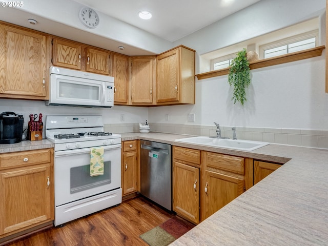 kitchen featuring dark wood finished floors, light countertops, recessed lighting, white appliances, and a sink